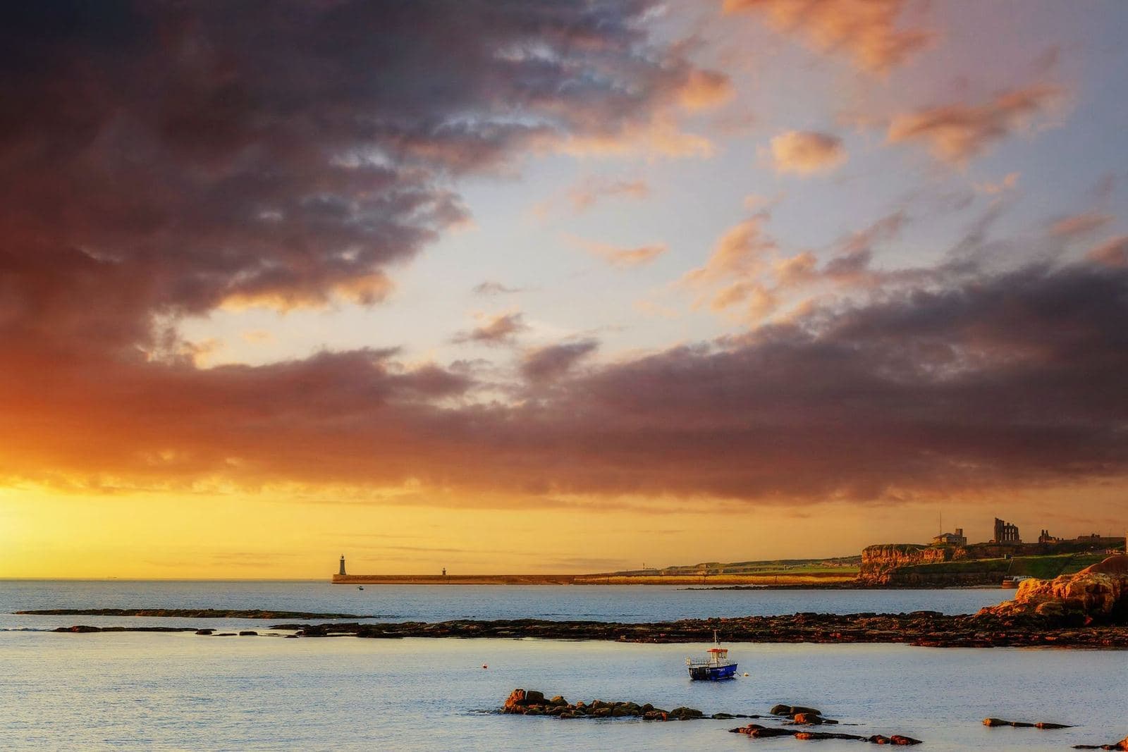 Tynemouth Priory headland and the North Pier lighthouse at sunset