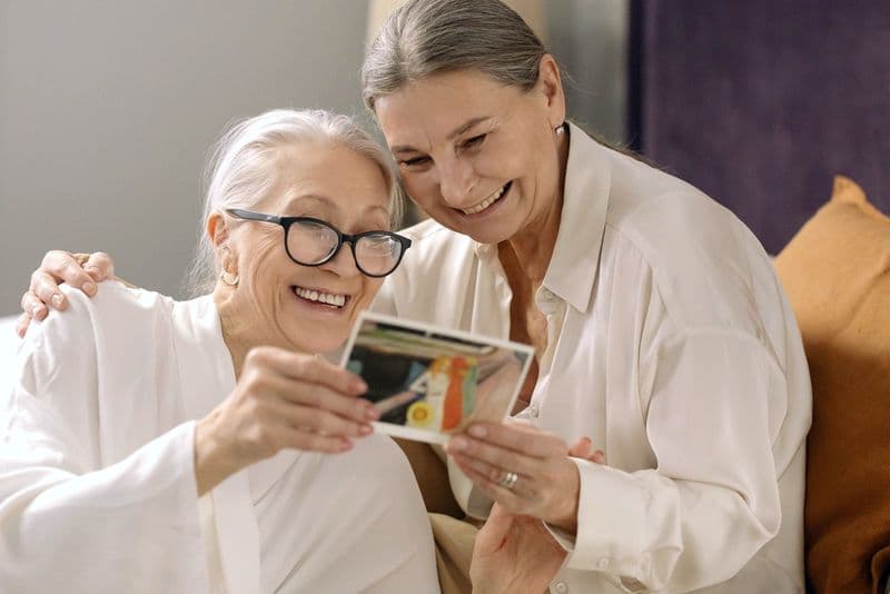 An older woman and a younger woman sorting something out together at a kitchen table
